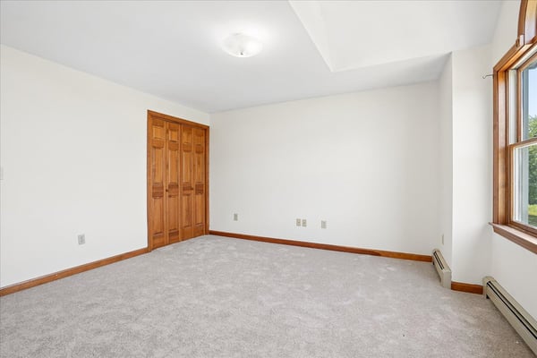Spacious room filled with natural light, featuring neutral tones and ample storage options for versatile use.