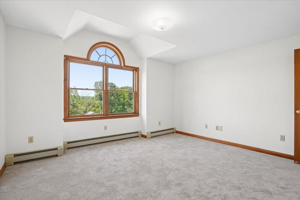Bright and airy room featuring large windows and plush carpet, perfect for creative space or cozy retreat.