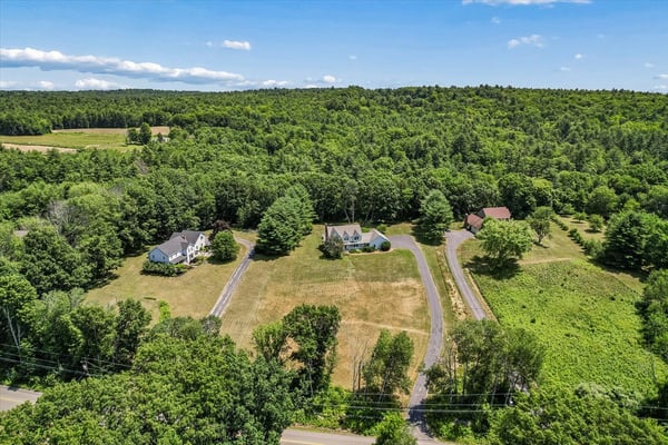 Spacious property surrounded by lush woodland, featuring multiple homes and expansive open space for various uses.