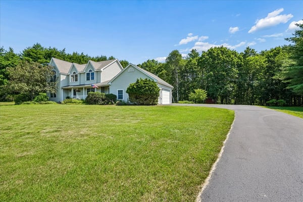 Spacious home on a large lot, surrounded by lush greenery and featuring ample parking options.
