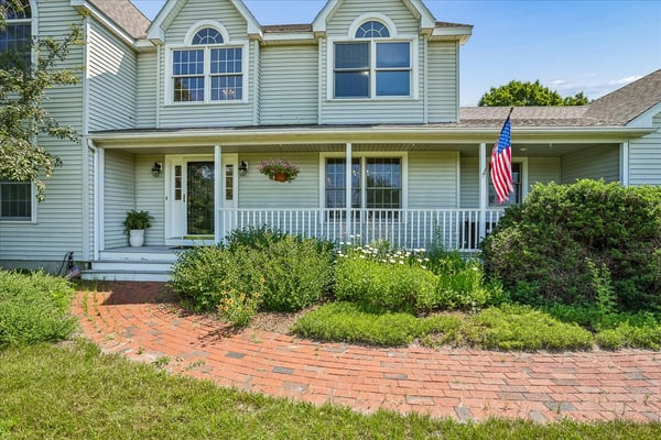 Spacious front porch with landscaped garden offers inviting outdoor space for relaxation and gatherings.