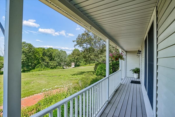 Enjoy expansive views from this spacious front porch, perfect for relaxing or entertaining amidst nature.