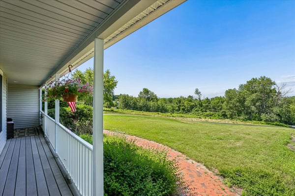 Enjoy expansive views and outdoor living from this welcoming wraparound porch, perfect for relaxation or entertaining.