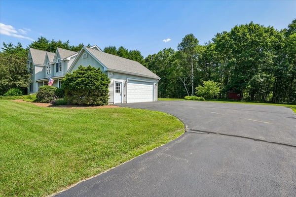 This spacious home features a circular driveway and lush landscaping, perfect for outdoor gatherings and privacy.