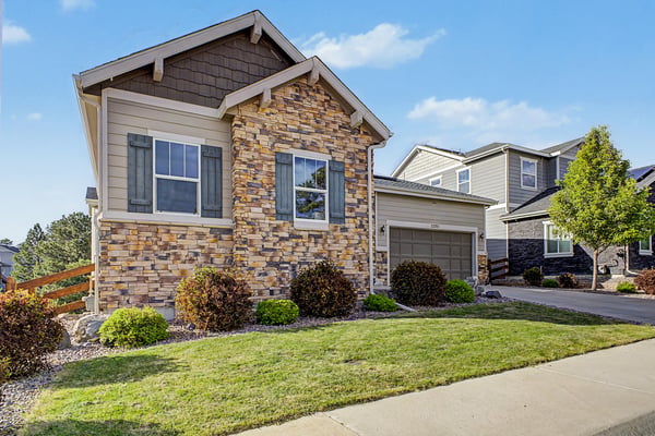 Modern home featuring natural stone accents, a well-maintained lawn, and proximity to neighborhood amenities.
