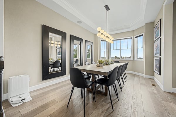 Bright dining area features modern decor with large windows, perfect for gatherings and enjoying natural light.