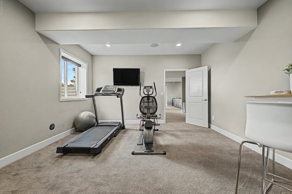 Furnished fitness room with exercise equipment and ample natural light, perfect for an active lifestyle.
