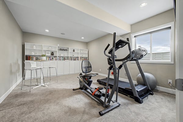 Spacious fitness room featuring modern equipment and ample natural light, ideal for workouts or relaxation.
