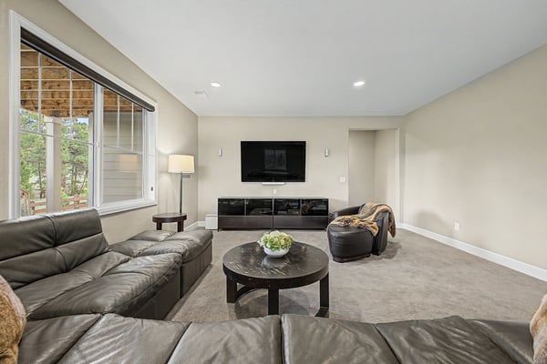 Spacious living area featuring comfortable seating, a sleek entertainment setup, and abundant natural light.