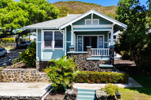Quaint bungalow featuring unique stonework, inviting porch, and lush landscaping in a picturesque neighborhood.