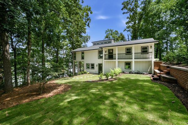 Modern home surrounded by lush greenery, featuring multiple outdoor spaces and ample natural light throughout.