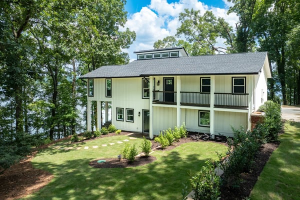 Modern waterfront home surrounded by lush greenery, offering stunning views and direct lake access for outdoor enthusiasts.