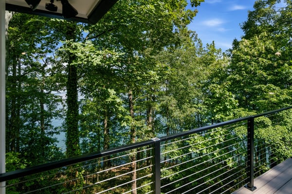 Discover a private balcony overlooking lush trees and tranquil water, perfect for nature lovers.