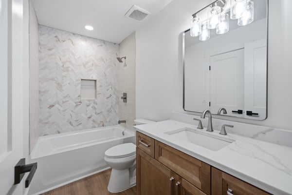 Modern bathroom featuring sleek marble tile, dual sinks, and a spacious tub for relaxation.