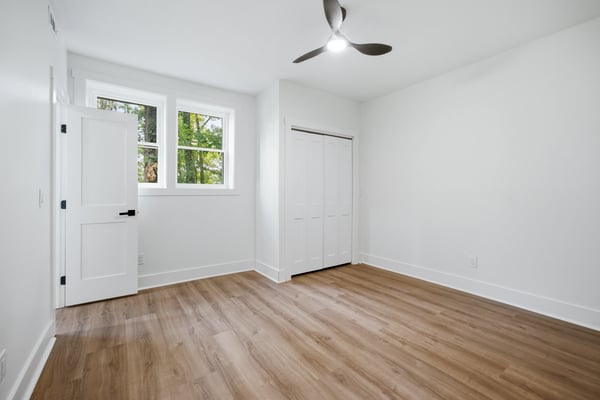 Bright, airy room featuring large windows, modern ceiling fan, and ample closet space for storage.