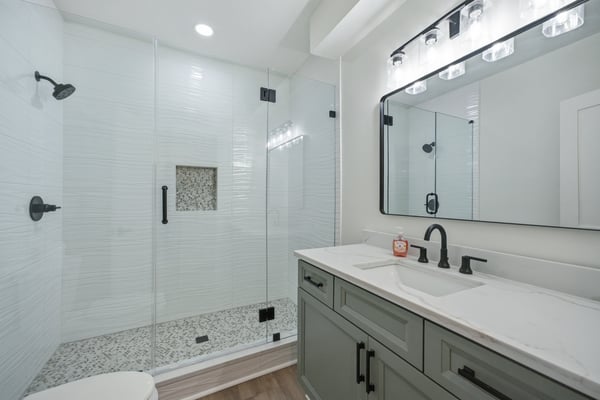 Modern bathroom featuring a spacious walk-in shower, sleek fixtures, and a polished marble countertop.