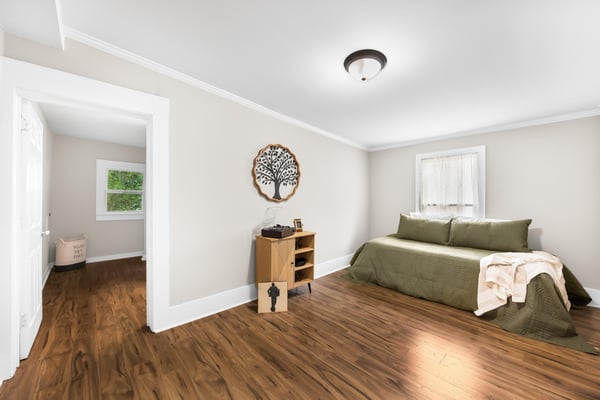 Bright and airy bedroom features warm wood floors, natural light, and a cozy atmosphere perfect for relaxation.