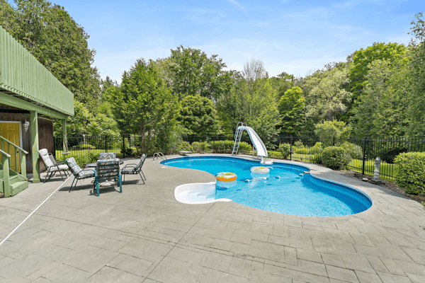 Enjoy summer days by the inviting pool featuring a slide, surrounded by lush greenery and relaxing loungers.