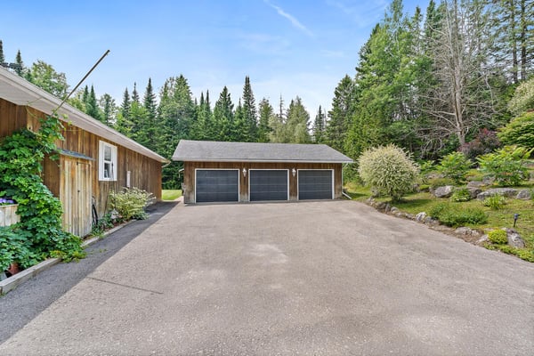 Spacious property featuring ample parking and garage space, surrounded by lush greenery and natural beauty.