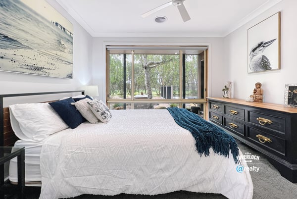 Spacious bedroom featuring large windows, natural light, and a view of lush outdoor greenery.