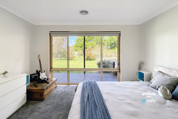 Bright bedroom featuring a large window with garden views, complemented by modern furnishings and cozy atmosphere.
