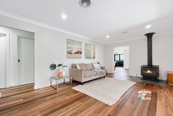 Spacious living area featuring hardwood floors and a cozy wood-burning stove, perfect for gatherings and relaxation.