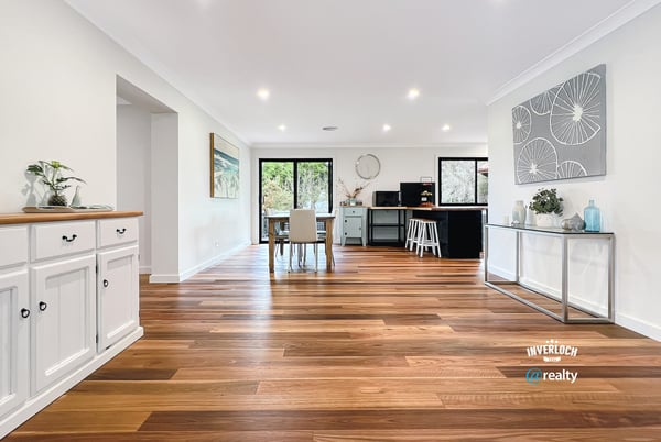 Spacious open-concept living area with warm wooden floors and abundant natural light, ideal for entertaining.