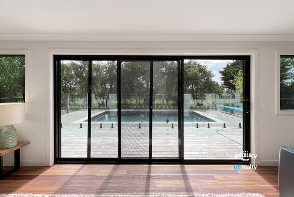 Bright and inviting living space with expansive glass doors opening to a private pool and outdoor deck.