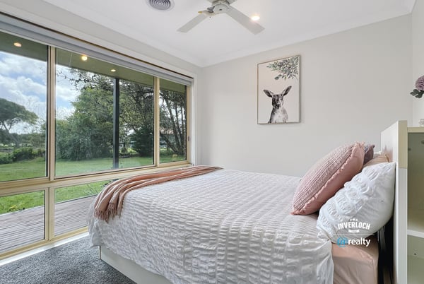 Bright and airy bedroom with large windows offering stunning views of the lush backyard.