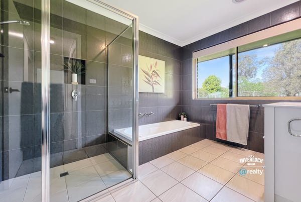 Modern bathroom featuring sleek tiles, a spacious shower, and large windows for natural light.