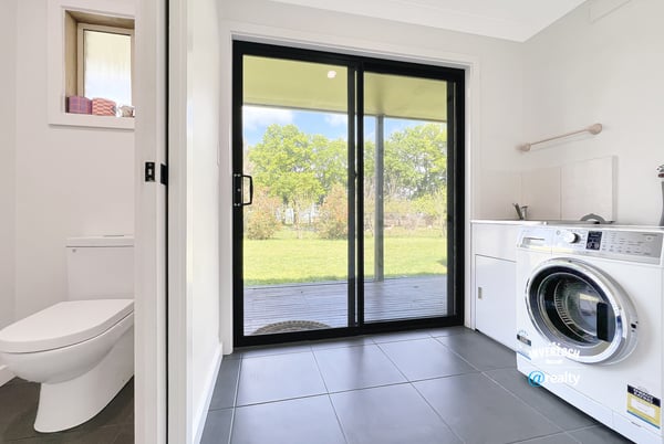 Bright laundry room featuring a washing machine, ample storage, and direct access to the outdoor space.