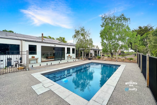 This contemporary home features a spacious outdoor area with a pristine pool and landscaped surroundings.