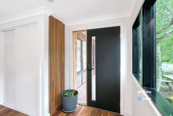 Contemporary entryway featuring a sleek front door and natural light enhancing the warm wooden floors.