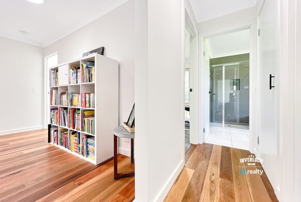 Bright and inviting interior featuring wooden floors, a spacious hallway, and a versatile bookshelf area.