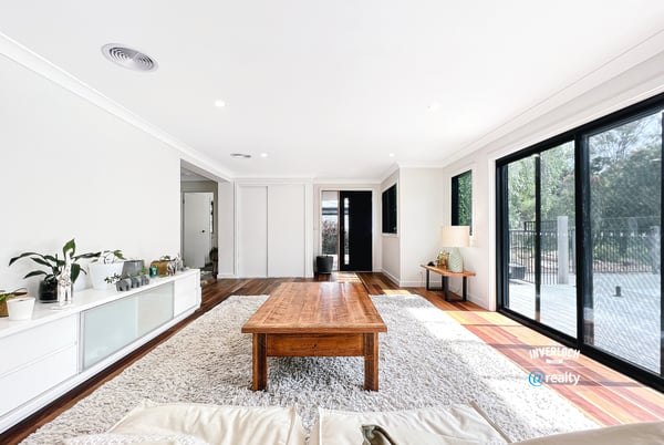 Bright open living space featuring large windows, natural light, and a warm wood coffee table.