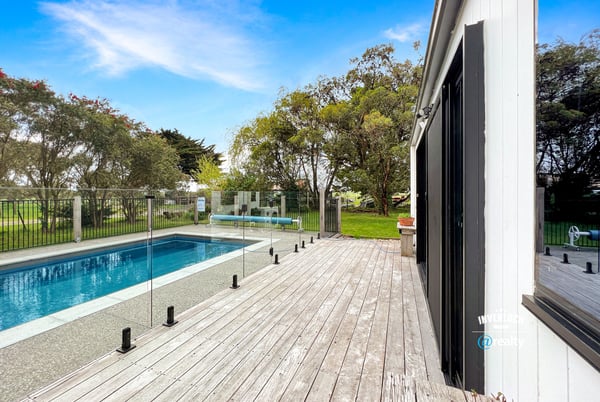 Discover a modern retreat featuring a spacious deck and inviting pool surrounded by lush greenery.