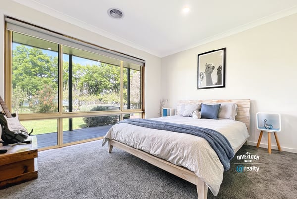 Bright and airy bedroom featuring large windows that invite natural light and offer picturesque garden views.