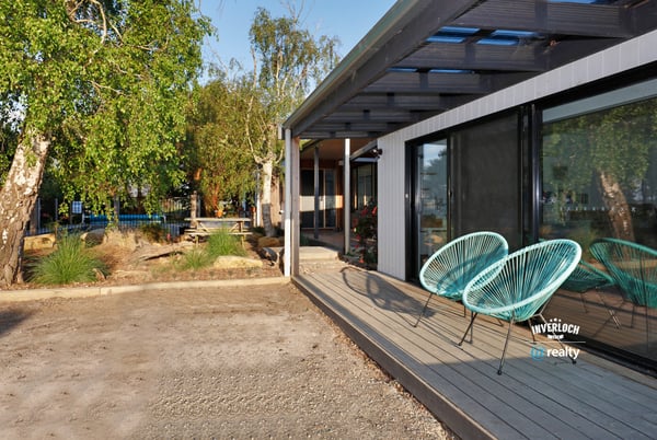 Discover this contemporary home featuring inviting outdoor seating and a spacious yard, perfect for entertaining.
