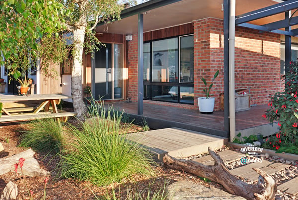 Contemporary home featuring expansive windows and an inviting outdoor space surrounded by lush greenery.