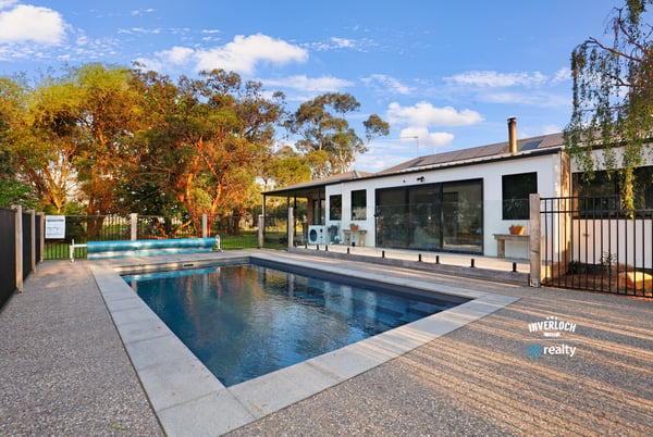 Contemporary home featuring an inviting pool area, surrounded by lush landscaping and ample outdoor space for relaxation.