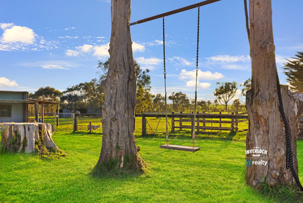Expansive property featuring a relaxing swing, surrounded by lush greenery and open countryside views.