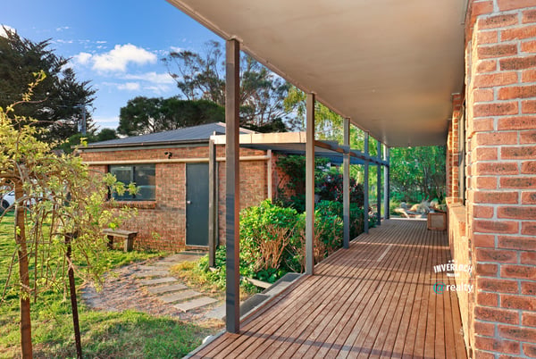 Spacious covered porch leads to a well-maintained garden, offering a welcoming entry to this unique property.