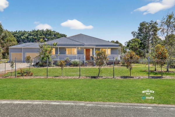 Spacious residence with a welcoming front porch, surrounded by landscaped gardens and ample parking options.