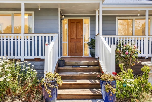 Welcoming entryway with landscaped flora, leading to a well-designed home filled with natural light.