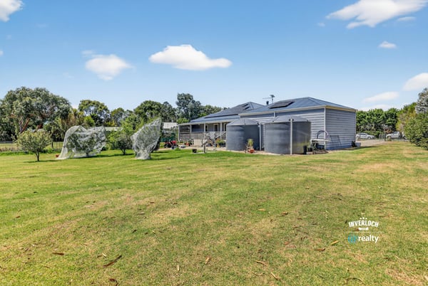 Spacious property featuring a well-maintained home, large yard, and multiple water tanks for convenience.