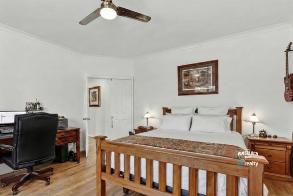 Bright and airy bedroom featuring a wooden bed frame and dedicated workspace, perfect for remote living.