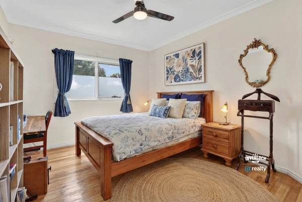 Cozy bedroom featuring a wooden bed, natural light, and a functional workspace for relaxation or productivity.