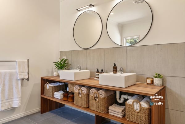 This modern bathroom features dual sinks, extensive storage, and a clean, minimalist design.