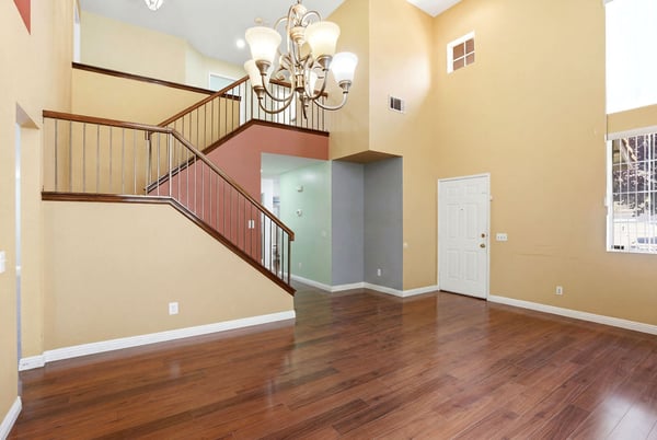 Spacious living area with high ceilings and an inviting staircase, perfect for entertaining and gathering.