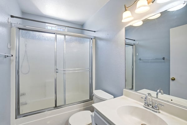 Bright and functional bathroom featuring a glass shower enclosure and ample natural light. Ideal for everyday use.